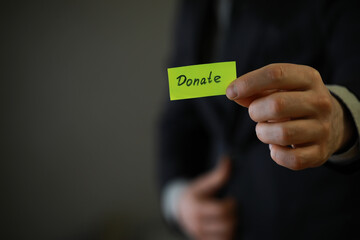 Businessman shows a paper with the word donate. Charitable donation in business concept.