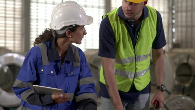 Young inspector female and foreman checking quality of metal sheet in factory