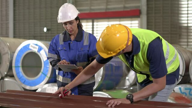 Young inspector female and foreman checking quality of metal sheet in factory