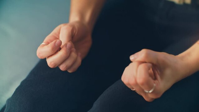 Nervous rubbing hands of a woman sitting on a blue therapy office sofa receives distressing news. Ideal for mental health awareness campaigns, counseling resources, and dramatic storytelling