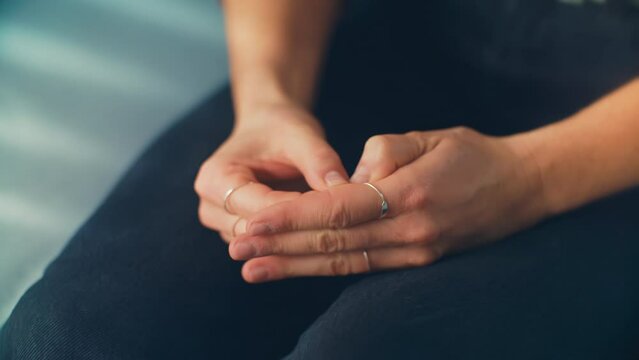 Nervous hands of a woman sitting on a blue therapy office sofa receives distressing news. Ideal for mental health awareness campaigns, counseling resources, and dramatic storytelling