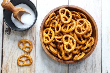 Crunchy pretzels in a black bowl are placed on a wooden table. A perfect salty party snack. copy space. crispy baked salt cookies or biscuits 