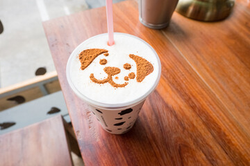 Puppy face of latte art cappuccino foam on wooden table.