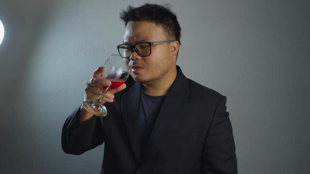 Close up portrait of young man with beard drinking red wine from glass. Businessman resting drinking wine. B roll Slow motion 4k.