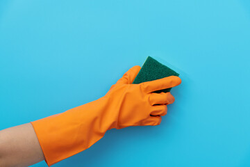 Hand holding sponge for cleaning on blue background - obrazy, fototapety, plakaty
