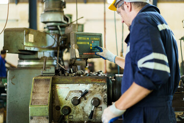 Professional caucasian white ethnicity male technician operating the heavy duty machine in the lathing factory. 