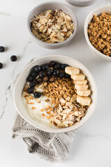 Homemade granola with Greek yogurt, almonds, blueberries and banana in a bowl. 