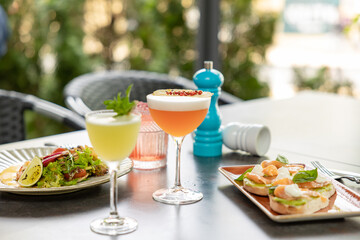The appetizing bruschettas and salad with refreshing drinks cocktails