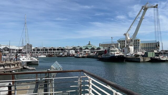 Heavy industrial port crane and catamaran yacht in the Cape Town Waterfront harbour