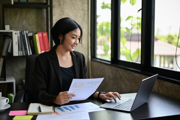 A professional Asian businesswoman focuses on her work, managing her marketing project