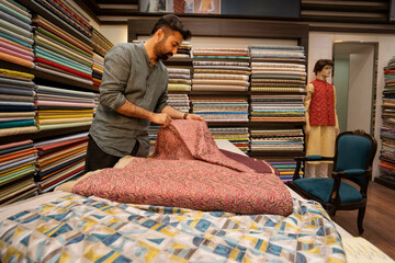 Man checking fabric rolls in a clothing store