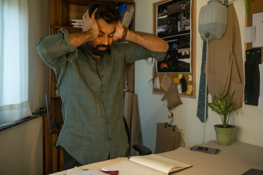 A male designer frustrated after working long hours in the studio 