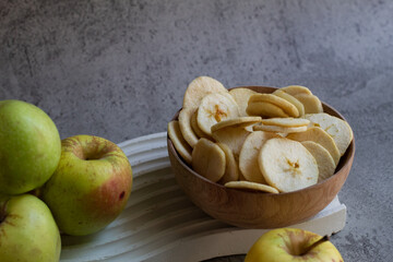 Apel Malang or Green apples and Yellow apple, slice and half of apple with apple chips in a wooden bowl  serving on wavy tray. isolated on gray background