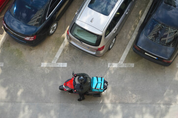 Delivery service. driver man in helmet with blue thermo backpack sitting on a moped . top view....