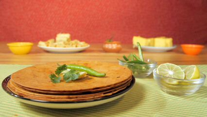 Fresh coriander leaves/Dhania dropping on some Khakras -  Gujarati snack. Closeup shot of traditional Indian breakfast made with wheat flour and oil placed beautifully on a plate