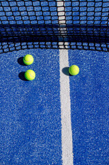 three balls near the net in a blue paddle tennis court, racket sports concept