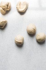 Dough balls on a marble countertop, making buns, process of making Swedish cinnamon buns or homemade Kanelbullar
