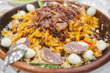 Rice with meat, carrots, onions, quail eggs and kazy in a plate of astau on the table. A traditional Uzbek dish called pilaf. A portion for three people.