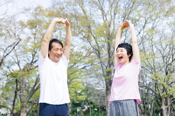 Fototapeta premium 公園で伸びる成熟した日本のカップル