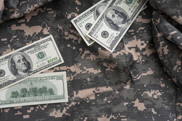 US dollar bills on fabric with texture of Ukrainian military pixeled camouflage. Cloth with camo...