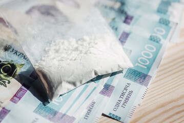 Plastic bag full of cocaine or other drugs on ukrainian money banknotes. Concept of trade of drugs, toned photo