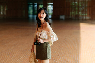 Portrait of asian young woman traveler with weaving hat and basket and a camera on street. Journey trip lifestyle, world travel explorer or Asia summer tourism concept.