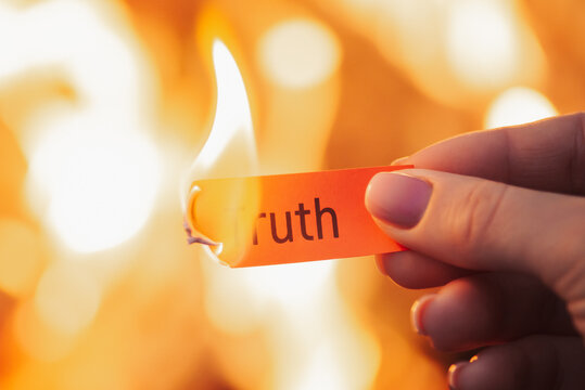 Burning paper in hands of a woman with word Truth. Hiding truth from someone, telling a lie concept