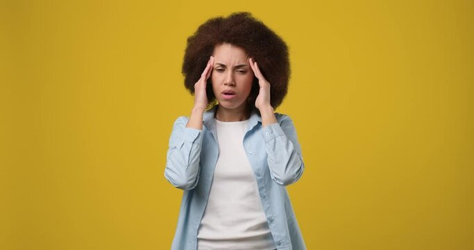Young african american woman having headache and massaging temples to relieve the pain isolated on orange studio background