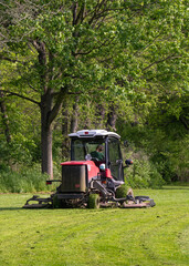 Professional gardener cutting green grass on lawn mower machine in park. High quality photo