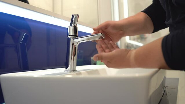 Closeup of male hands opening tap faucet in bathroom, having no water in house. Water supply problems and household debt concept 