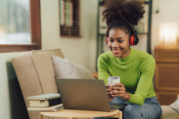 Focused young African female college student working on a laptop on living room.