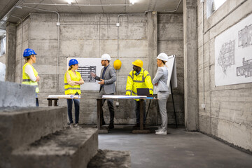 Construction site meeting. Team of experienced architects, engineers and workers analyzing...