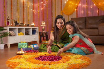 Beautiful mother and daughter making rangoli on diwali festival - Colorful background. Image of...