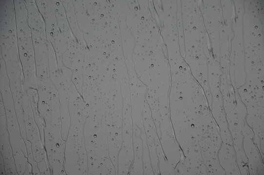 Regen f&auml;llt: Wasser rinnt an Scheibe runter bei grauen Regenwetter.