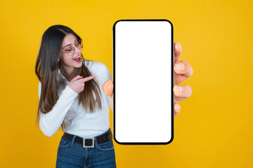 Holding big blank cell phone, cheerful caucasian woman holding big blank cell phone. Millennial lady pointing finger smartphone mockup. Recommending new application, mobile website, online shopping. - obrazy, fototapety, plakaty