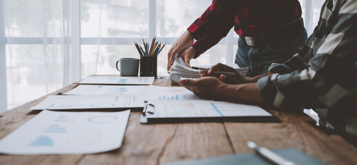 Team work process, business team using calculator to calculate figures of business statistics, profit, growth rate graph document. information charts on the office desk.