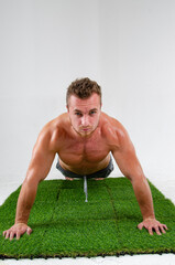 A young handsome guy does exercises on the abdominal muscles. A man with a beautiful athletic body.