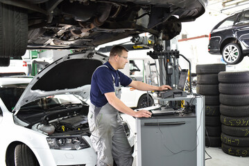 car mechanic maintains a vehicle with the help of a diagnostic computer - modern technology in the...