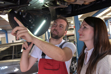 mechanic and customer talking in a workshop to repair a vehicle