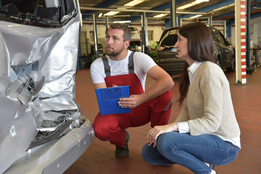 Customer service: car mechanic and woman discuss car repair after a traffic accident