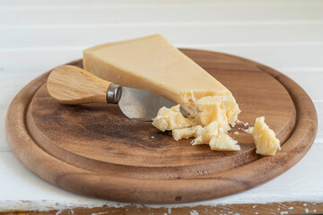 Parmesan cheese with knife on wooden background.