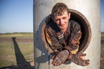 a working industrial climber taking a smoke break from painting a water tower. difficult work in a...