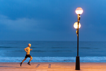 Sportsman running at night through coastline