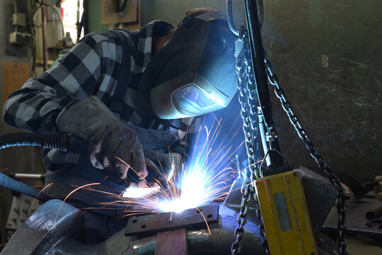 Welder in protective clothing at the workplace in an industrial company in steel construction