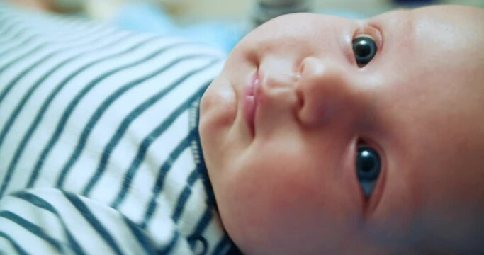 A little boy three months old, close-up looks into the frame. Serious face. A beautiful baby is looking at the camera.