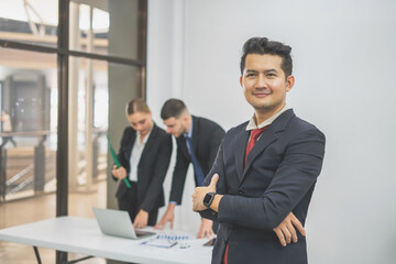 Fototapeta premium Group of Smiling Businessmen Working on Laptops at Desk in Office With Caucasian Colleagues using Digital Tablet During General Project Meeting