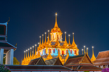 The Loha Prasat, Wat Ratchanatdaram Worawihan at night that is turning on a beautiful yellow light which is one of the famous temples in Bangkok