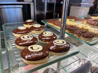 Assorted glazed donuts with chocolate sprinkles topping inside a shop counter