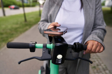 Unrecognizable woman using mobile phone to use a electric scooter