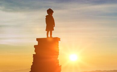 Back to school. silhouette inquisitive child stands on stack of books and looks into bright future...